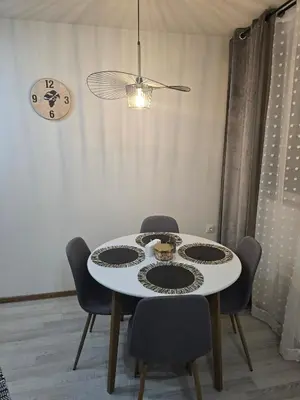 a dining room table with chairs and a clock on the wall at Peshtera Cozy Apartment in Peshtera