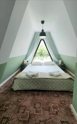 a bedroom with a bed with a triangular window at Magnika in Sapareva Banya