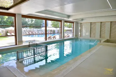 a large swimming pool in a house with windows at Ивелия Хотел и Спа - Ivelia Hotel & SPA in Dŭbnitsa