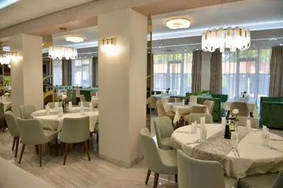 a restaurant with white tables and chairs and chandeliers at Ивелия Хотел и Спа - Ivelia Hotel & SPA in Dŭbnitsa