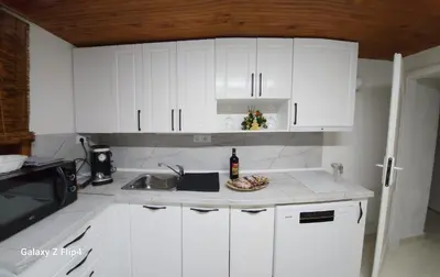 a white kitchen with white cabinets and a sink at Guest Suite SUZY in Petrich