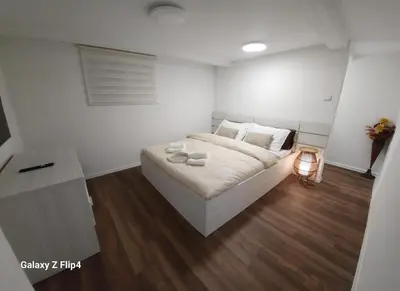 a bedroom with a bed with white walls and wooden floors at Guest Suite SUZY in Petrich