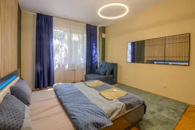 a bedroom with a bed and a chair and a tv at 2 DeLuxe Apartments, Top Center Free Parking, 4 BDR in Sofia