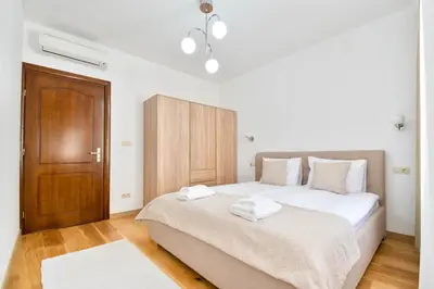 a bedroom with a bed with white sheets and a wooden door at Apartment Central in Plovdiv