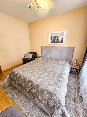 a bedroom with a large bed and a chair at Apartment GORA in Borovets