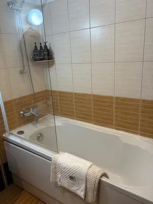 a bathroom with a bath tub with a glass shower at Apartment GORA in Borovets