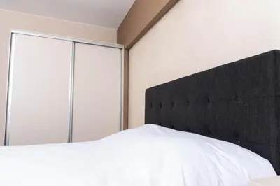 a bedroom with a white bed with a black headboard at Apartment Maritsa View 1 in Plovdiv