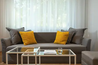 a living room with a gray couch with yellow pillows at Starflat Gorgeous central apartment next to NDK in Sofia