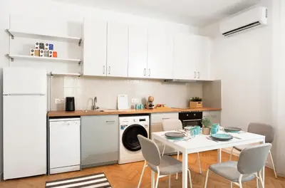 a kitchen with white cabinets and a white table and chairs at Starflat Gorgeous central apartment next to NDK in Sofia