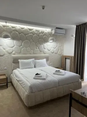 a bedroom with a large bed with a stone wall at Stillaterm SPA in Mineralni Bani