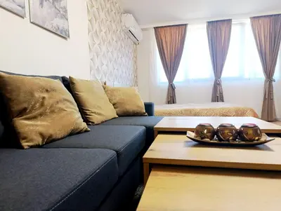 a living room with a blue couch and a table at Moderno Studio Park Lane in Bansko