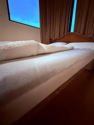 a bed with white sheets and a window at Central Mansard Studio in Sofia