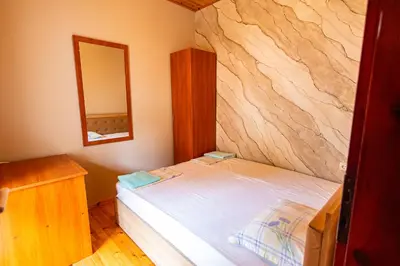 a bedroom with a bed with a stone wall at Комплекс Родопска среща - Къщи и Апартаменти in Batak