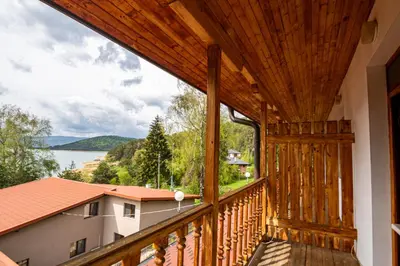 a wooden balcony with a view of the water at Комплекс Родопска среща - Къщи и Апартаменти in Batak