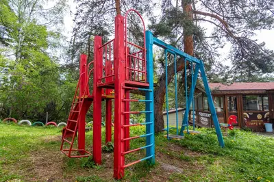 a playground with red and blue equipment in a park at Комплекс Родопска среща - Къщи и Апартаменти in Batak