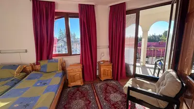 a bedroom with a bed and a window with red curtains at Maisonette on the slope in Manastir 3 in Pamporovo