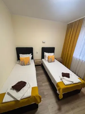 two twin beds in a room with a window at Къща за гости Elion House in Hisarya