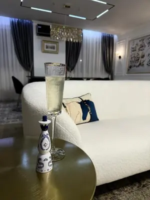 a glass of water on a table next to a bed at Grand Trio Apartment in Plovdiv