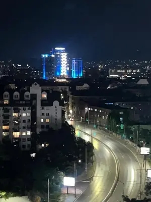 a city street at night with illuminated buildings and street lights at Cozy apartment with balcony and panoramic view in Sofia