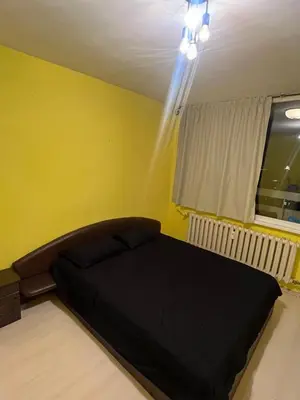 a bedroom with a black bed in a yellow wall at Cozy apartment with balcony and panoramic view in Sofia