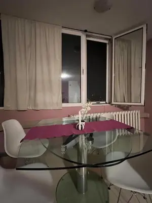 a glass table in a room with chairs and windows at Cozy apartment with balcony and panoramic view in Sofia