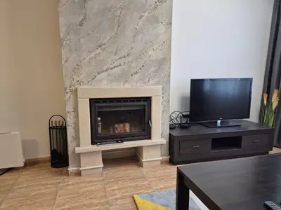 a living room with a fireplace and a flat screen tv at 1А1 Apartament in Pamporovo