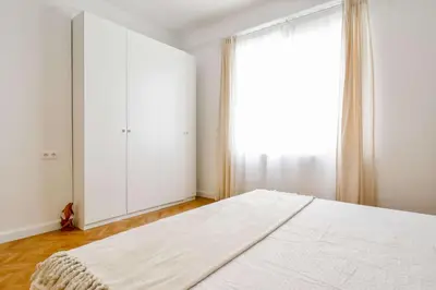 a bedroom with a white bed and a large window at Lift - Duplex - King Beds - 5min to Vitosha in Sofia