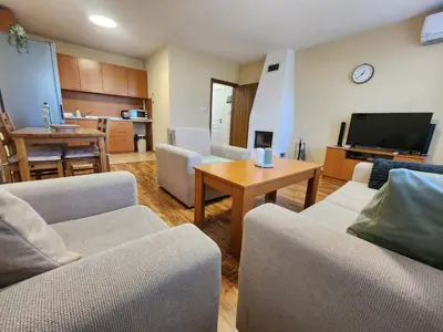 a living room with couches and a television and a table at Mountain Dream apartment near ski road in Bansko