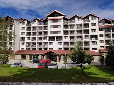 a large apartment building with cars parked in a parking lot at Apartment E45 in Borovets Gardens, Borovets resort in Borovets