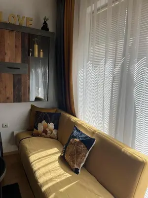 a couch with pillows on it in a living room at ТРИ ПЛАНИНИ ап113 in Razlog