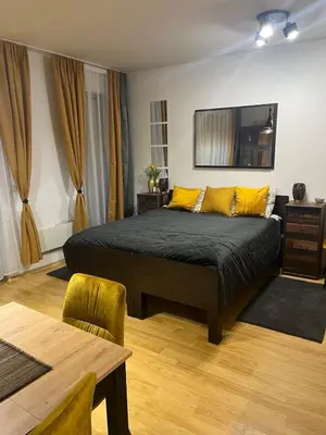 a bedroom with a bed with yellow pillows and a table at ТРИ ПЛАНИНИ ап113 in Razlog