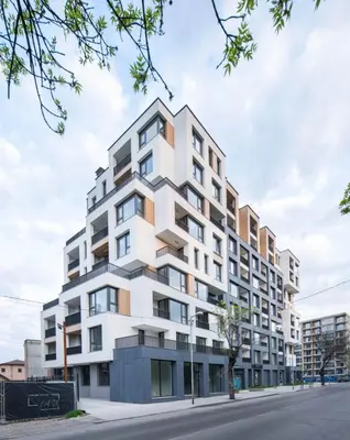 a tall white building on a city street at The Corner apartments in Sofia