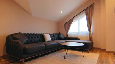 a living room with a black couch and a table at Къща за гости Станковата къща in Belchin