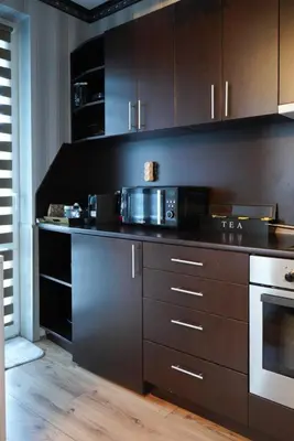 a kitchen with dark brown cabinets and a microwave at Pirin Elegance Apartment by Gondola Lift in Bansko