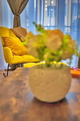 a table with a yellow couch and a vase of flowers at The Heart of Sofia just steps away from Vitoshka in Sofia