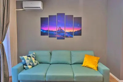 a blue couch in a living room with paintings on the wall at The Heart of Sofia just steps away from Vitoshka in Sofia