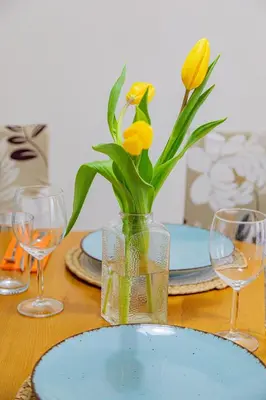 a table with a vase with yellow flowers in it at Студио 8 Уютна Почивка in Hisarya