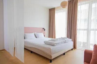 a white bedroom with a bed with towels on it at Студио 8 Уютна Почивка in Hisarya