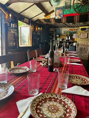 a long table with plates and a bottle of wine at Дядо Пановата къща