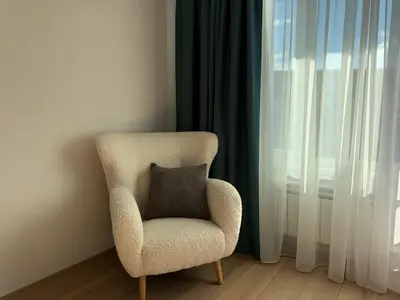 a chair with a pillow sitting next to a window at SkyWay by NightSpace- Modern City Apartment in Sofia