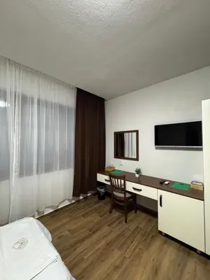 a room with a bed and a desk and a tv at Комплекс Ванката in Kamena