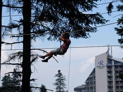 a man on a zip line near a tree at Borovets Apartments, Flora Violet Residence in Borovets