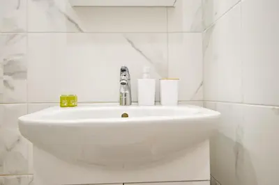 a white sink in a white tiled bathroom at Armand de Sanelle in Sofia