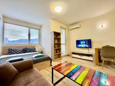 a room with a bed and a tv and a couch at Joyful Studio in Sofia