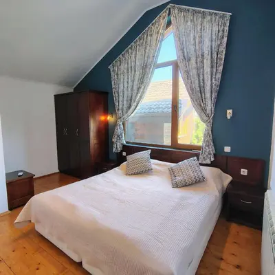a bedroom with a large bed with a window at Fairytale Cottage in Redenka in Razlog