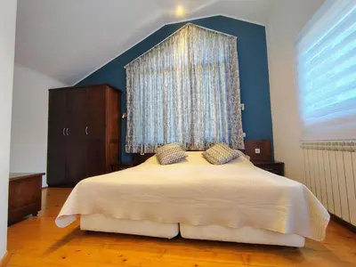 a bedroom with a large bed with a blue wall at Fairytale Cottage in Redenka in Razlog