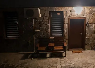 a stone wall with a bench in front of a door at Апартамент Милена in Smolyan