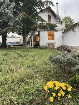 a white house with yellow flowers in the yard at Country House БатЖоро