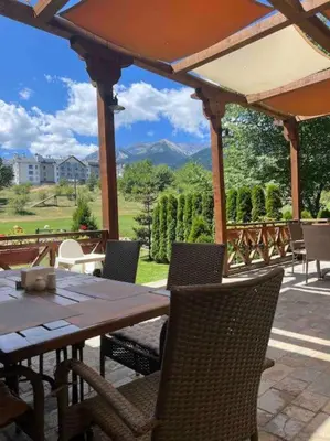 a wooden table and chairs on a patio at Appartement moderne et chic Ski & Spa Bansko in Bansko