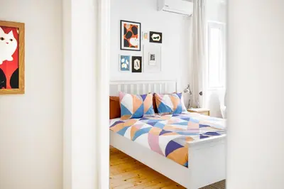 a white bedroom with a bed with colorful pillows at Boho Gem in Sofia